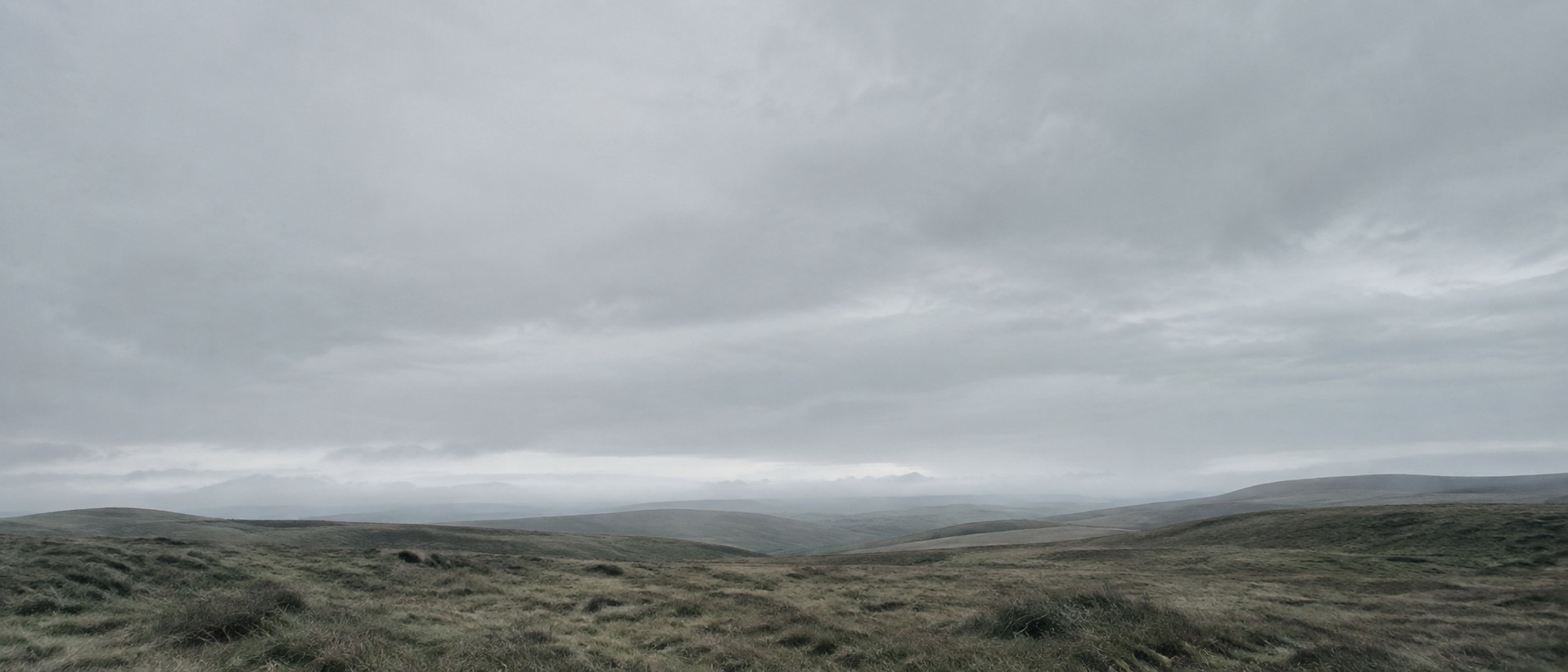 Wide open moorland under a heavy overcast sky, with a low horizon and no building or landmark in sight.