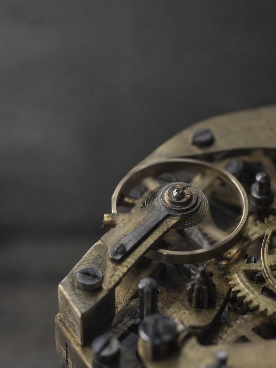 The exposed brass and steel movement of a mechanical clock, seen close, with its gear train and balance wheel.