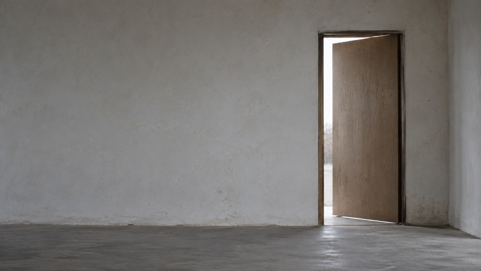 A plain door standing slightly ajar in a blank wall, with daylight showing in the gap.